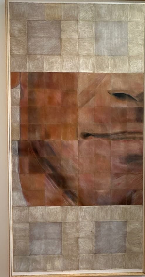 A portrait emerging from a grid of woven paper tiles in warm skin tones, fading to white at the edges.