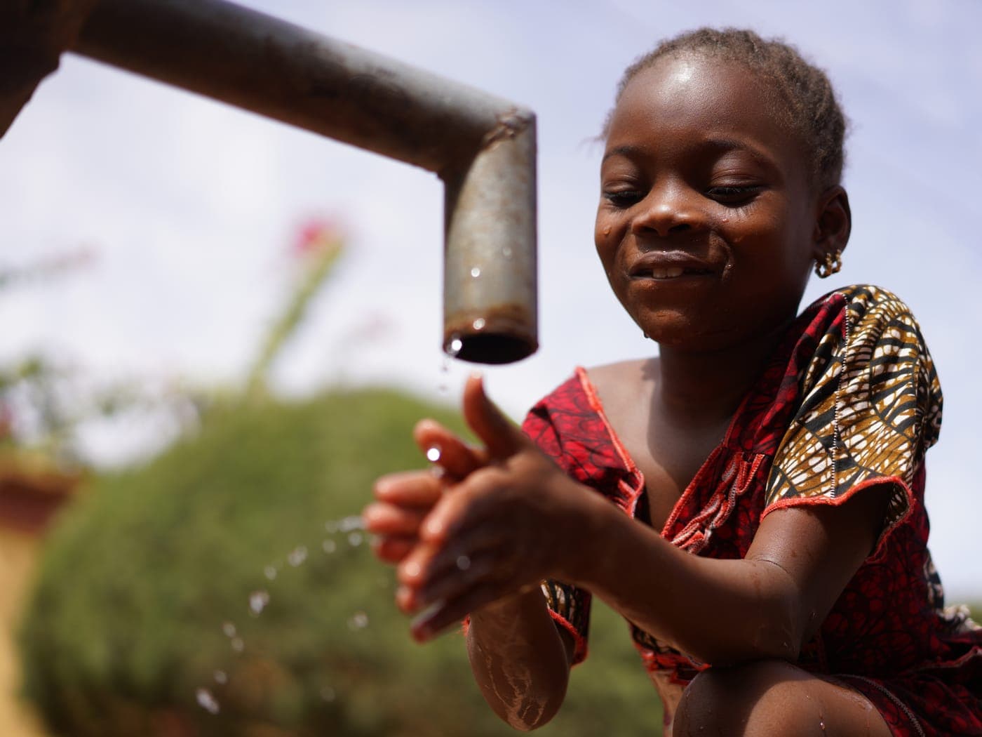 A young girl drinking clean water from a household tap.